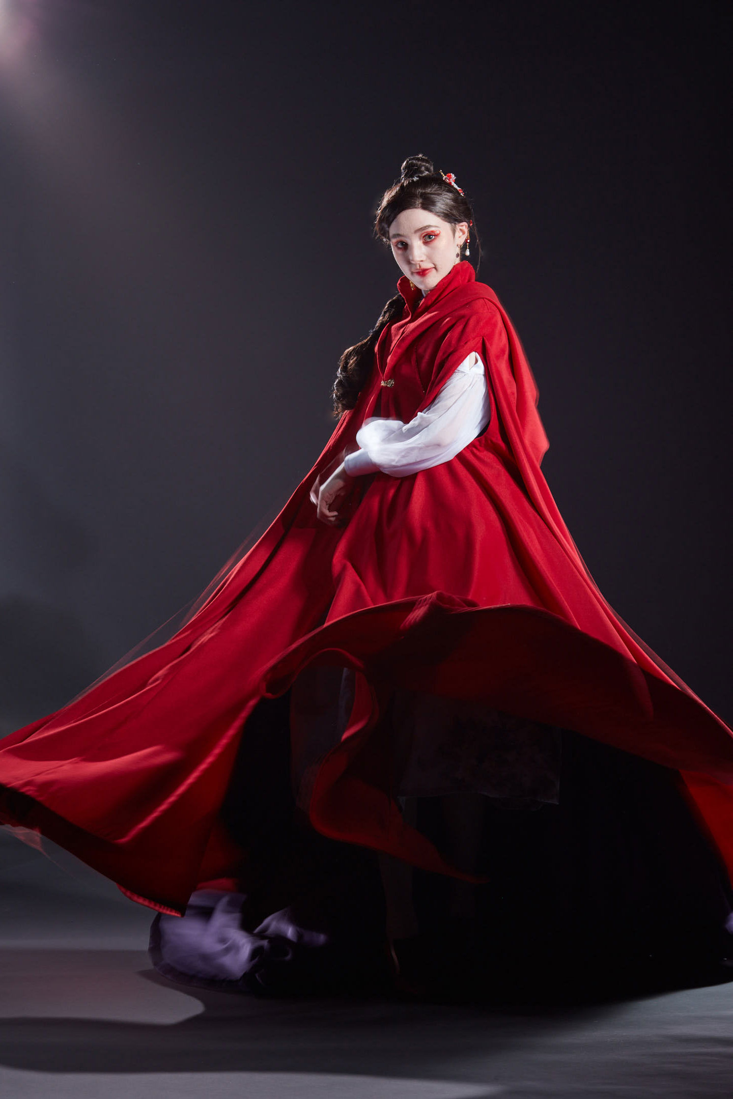 The model spins in a vibrant red cloak that billows around her.