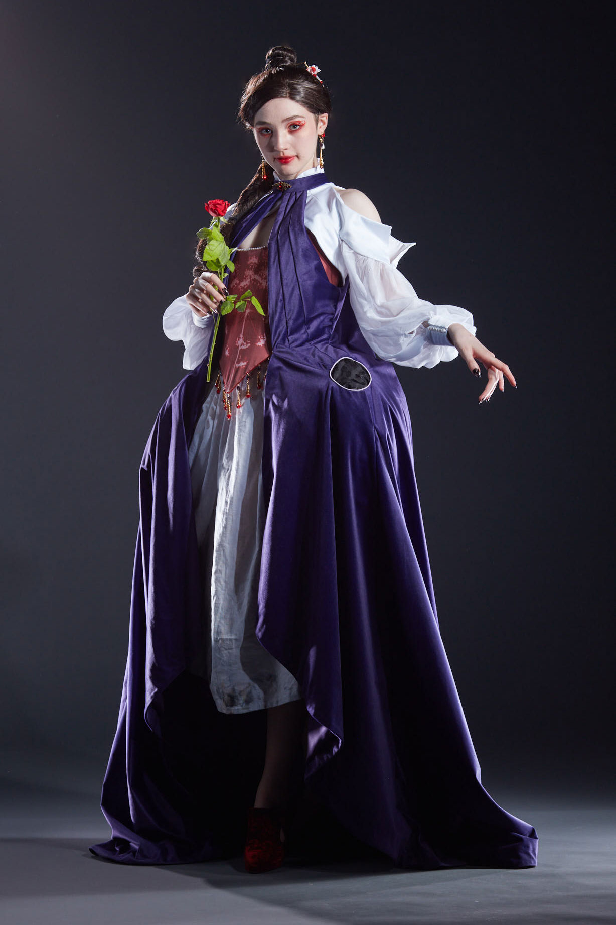 The costume created for the character Lacie from Pandora Hearts. The model wears a purple dress with a red corset, white skirt and sleeves. 