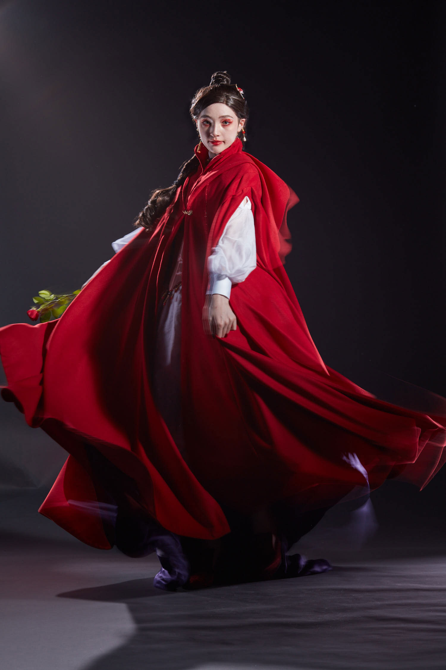 The model spins in a vibrant red cloak that billows around her.
