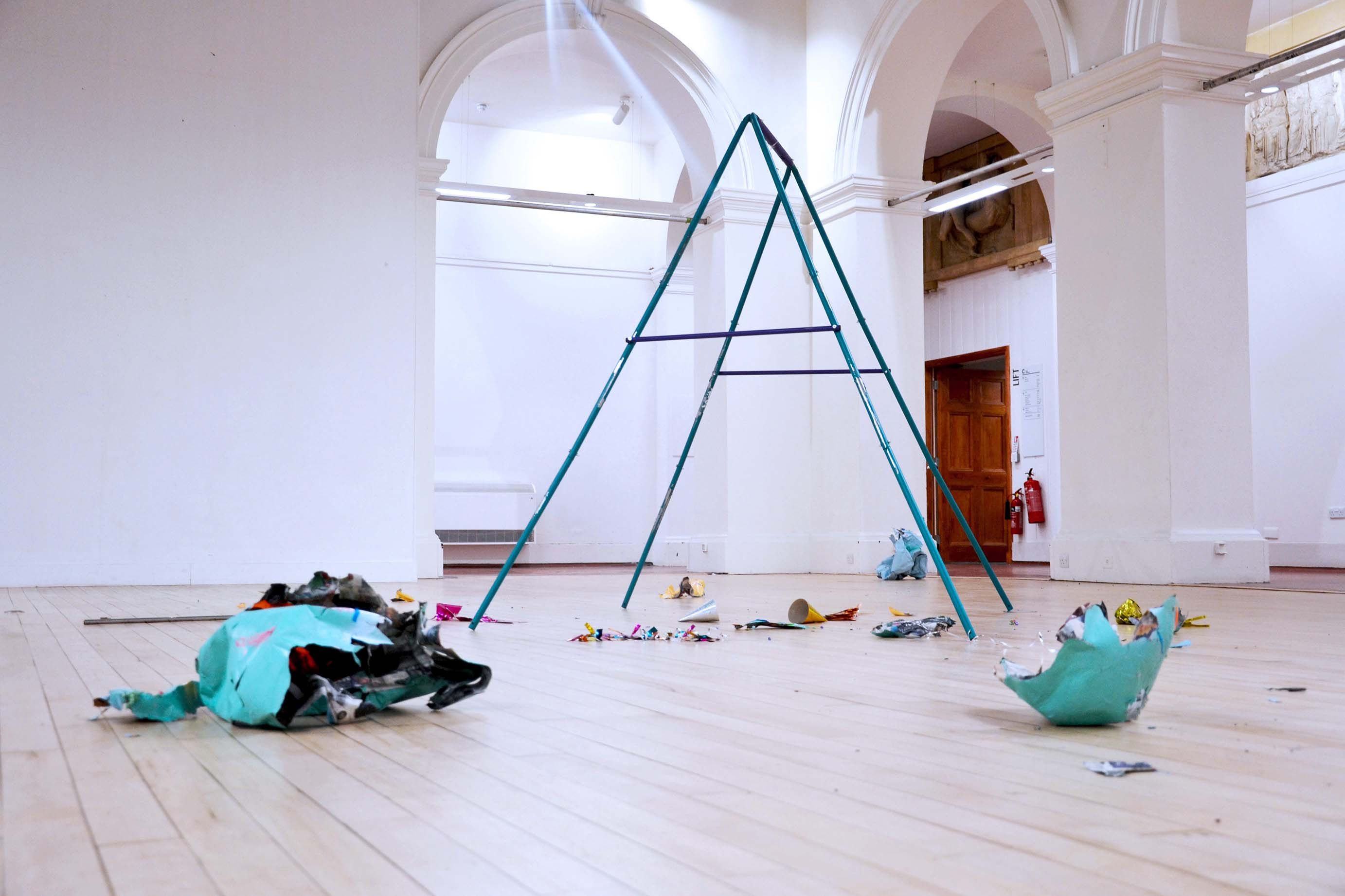 RUNNING ON EMPTY, 2022 - Steel swing set, fragments of spray paint on papier mâché, slime, bouncing putty, party decorations