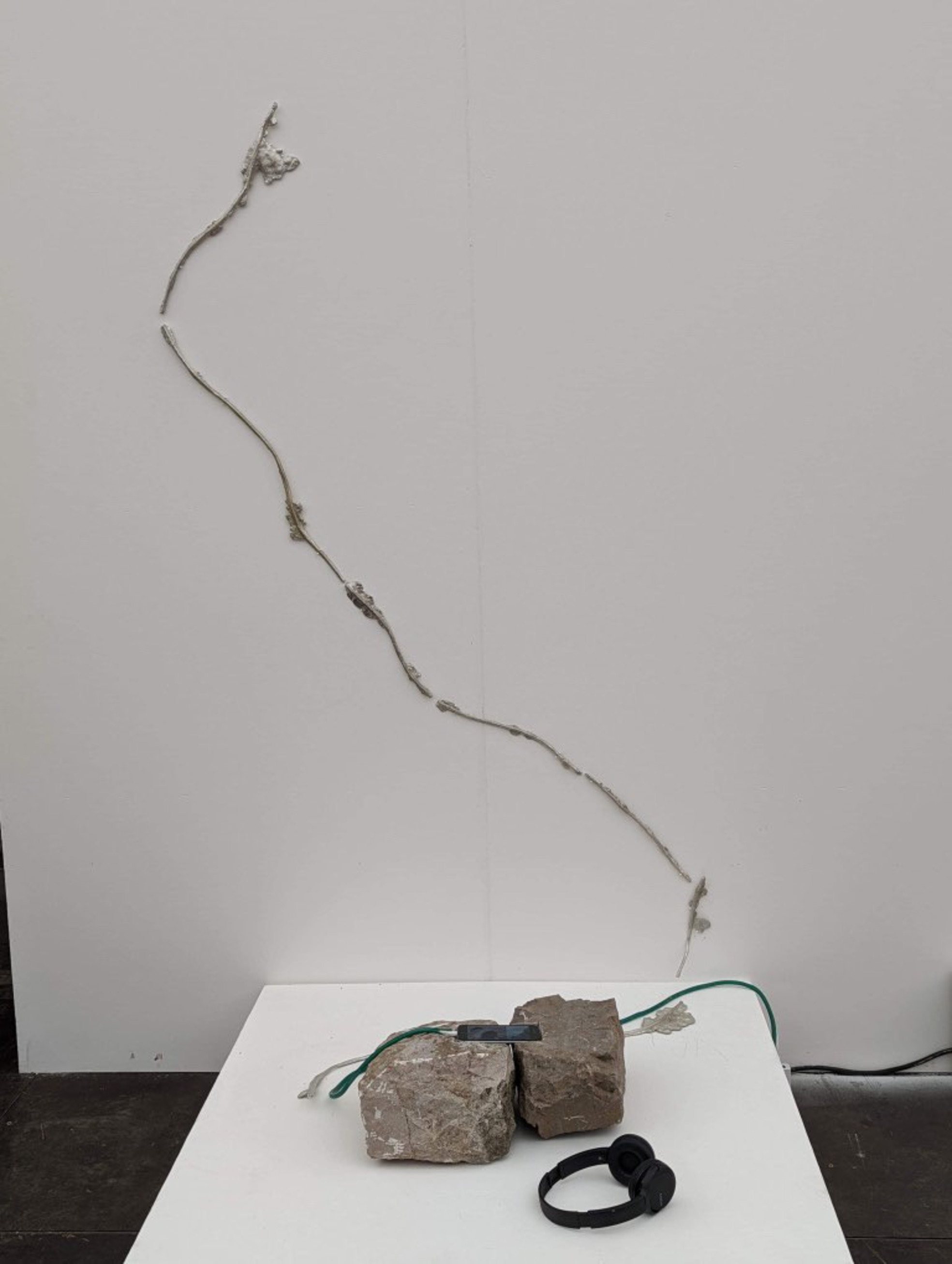Limestone with phone screen between, pewter wire casts on the wall behind